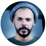 photo portrait d'un jeune homme dégarni avec un bonnet bleu sur la tête, une barbe brune