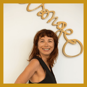 portrait d'une femme blanche qui affiche un large sourire, avec les cheveux mi-longs de couleur auburn et une frange, elle porte un débardeur noir. elle est de profil, et son visage nous fait face.